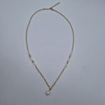 Collier en chaîne dorée avec pendentif perle et détails raffinés